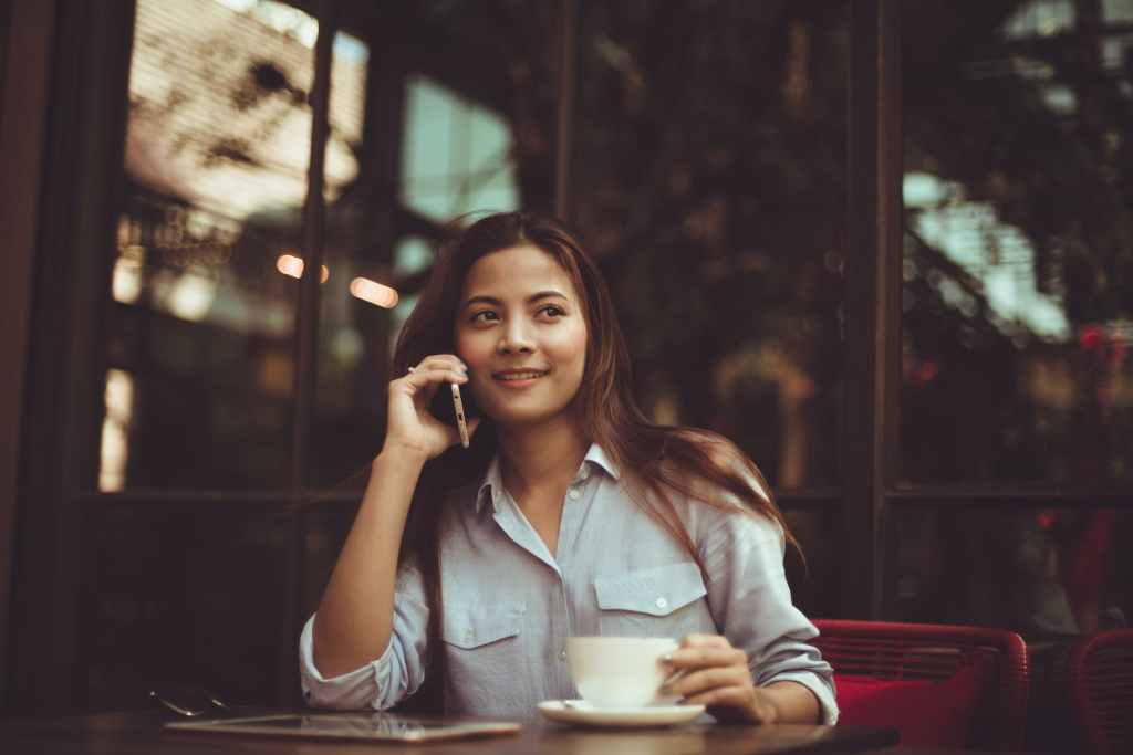 portrait of young woman using mobile phone in cafe